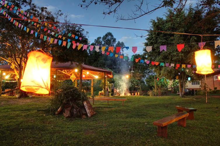 Festa Junina no campo com pessoas dançando quadrilha e decoração típica.