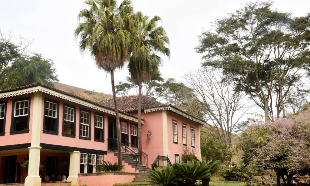 Fazenda histórica no Brasil rodeada por natureza exuberante, representando o patrimônio cultural rural.