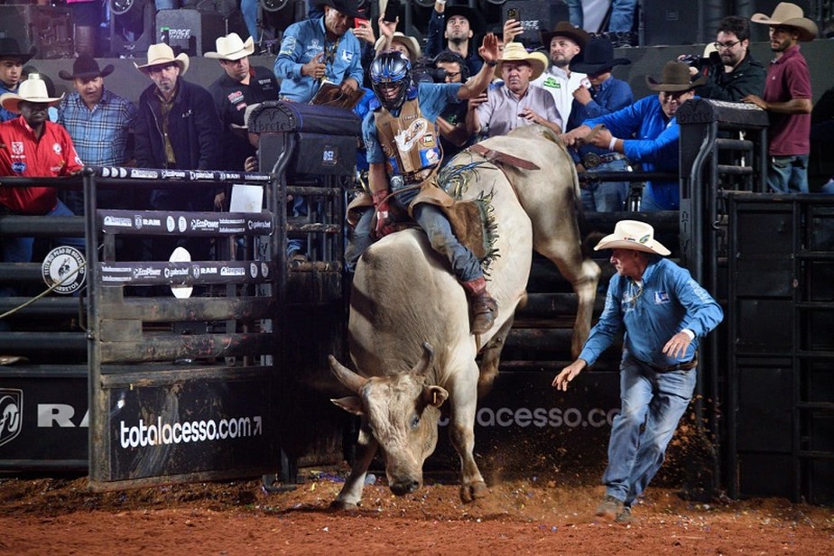 Cavaleiros em um rodeio brasileiro, montando em touros durante uma intensa competição