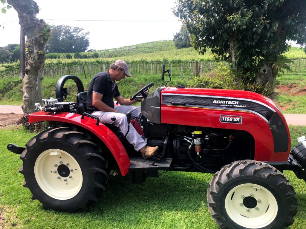 Trator agrícola em um campo verde, ressaltando a importância da manutenção preventiva para aumentar a rentabilidade.