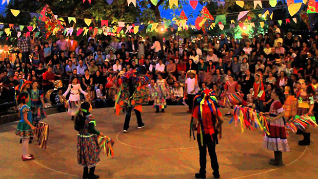 Festas Juninas no campo com fogueira, bandeirinhas e comidas típicas.