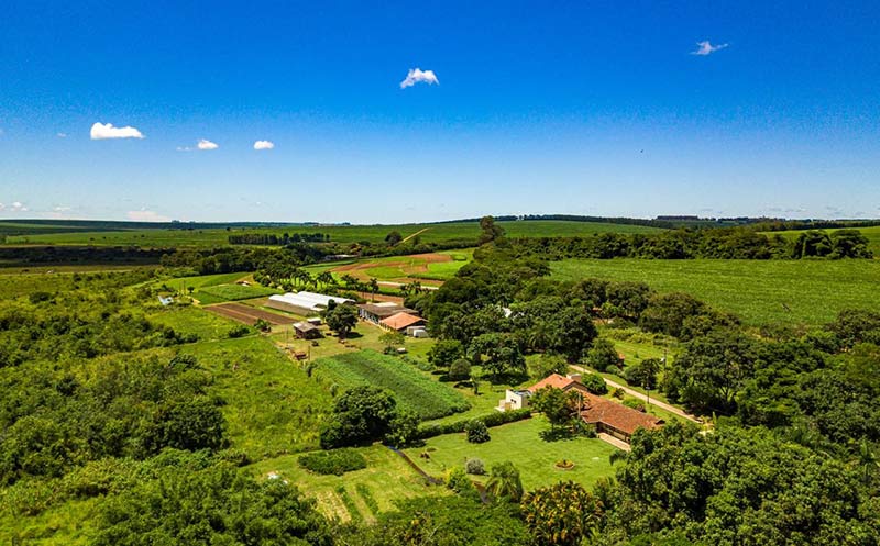 Fazenda de turismo sustentável com vegetação exuberante e estruturas rústicas