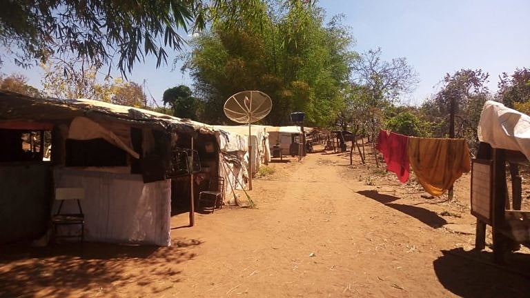 Trabalhadores rurais em um acampamento rural com paisagens campestres ao fundo.