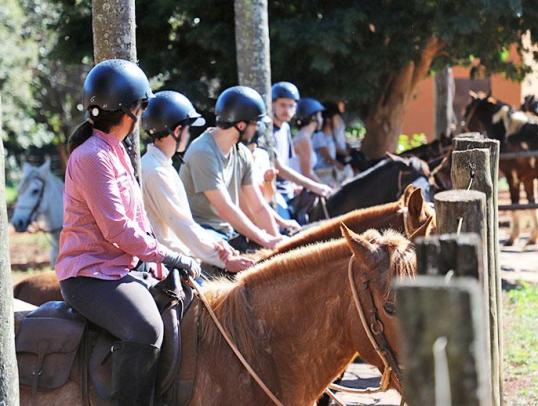 Cavalgada social em um cenário rural, com pessoas em cavalos desfrutando da natureza.