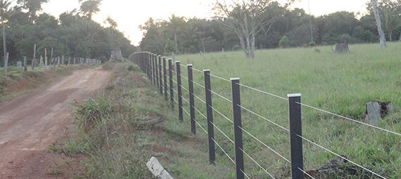 Construção de cercas em uma propriedade rural, mostrando arame liso e madeira.