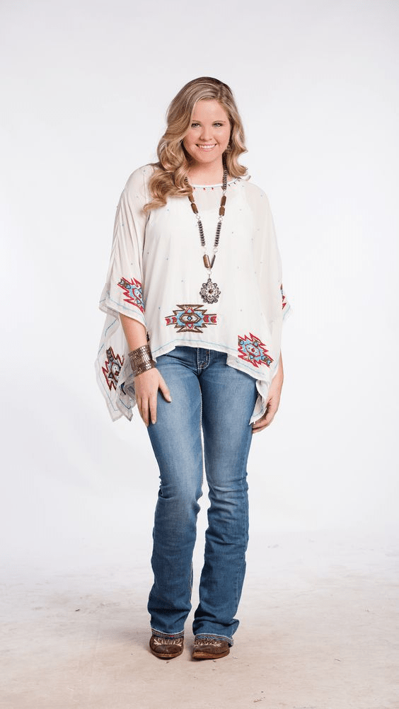 Modelo plus size vestindo roupas típicas country em um cenário rural com paisagem de fazenda.