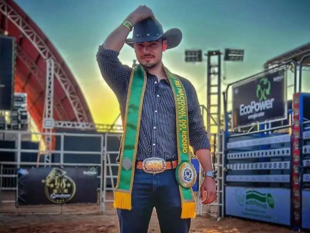 Um cowboy participando de um rodeio, vestido com roupas tradicionais e montado em um cavalo.