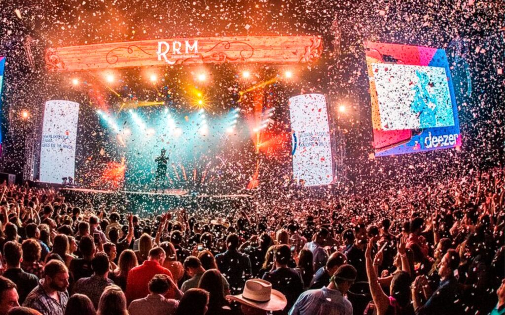 Um vibrante show de música country ao ar livre, com artistas se apresentando sob luzes brilhantes.