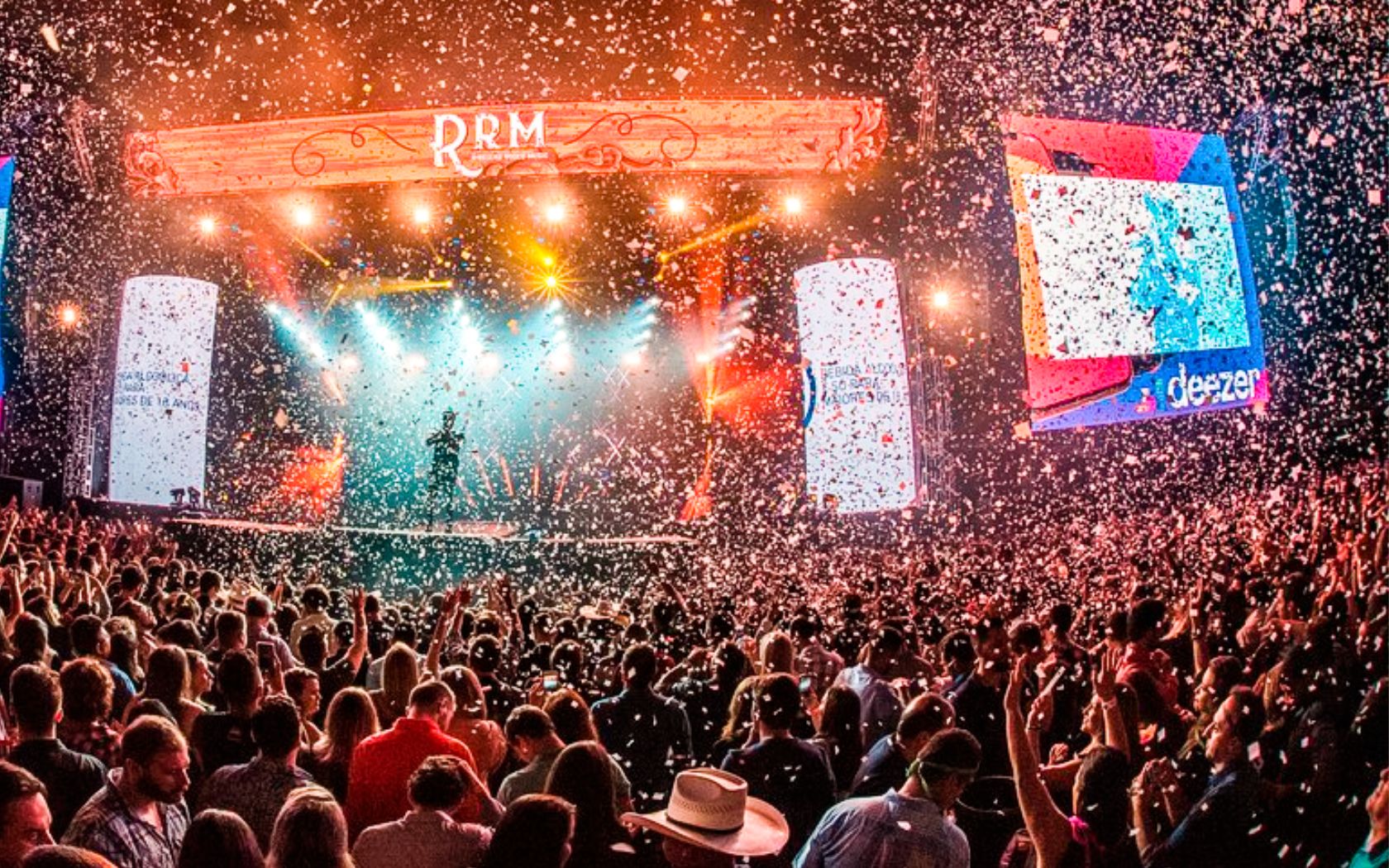 Um vibrante show de música country ao ar livre, com artistas se apresentando sob luzes brilhantes.