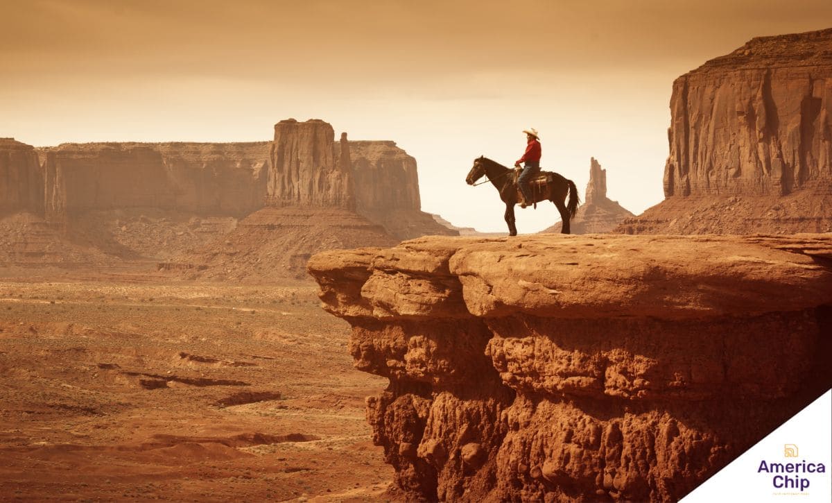 Um cowboy montando em um cavalo em um vasto campo com uma paisagem rural ao fundo