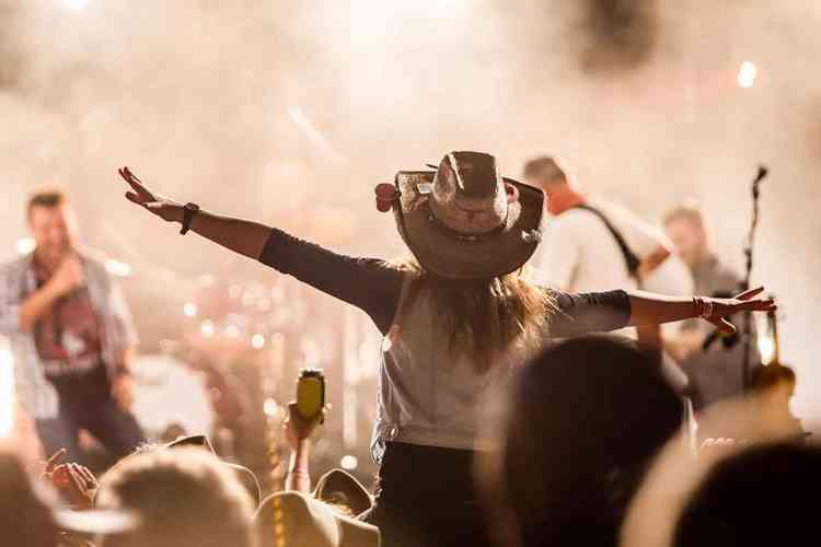 Uma apresentação musical country com artistas brasileiros no palco, celebrando a cultura country no Brasil.