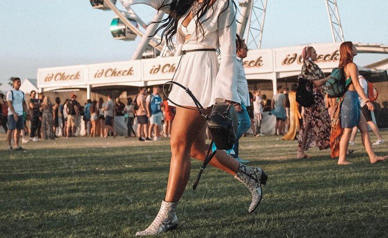 Modelo vestindo roupa country em um cenário rural, com jeans, bota e chapéu.