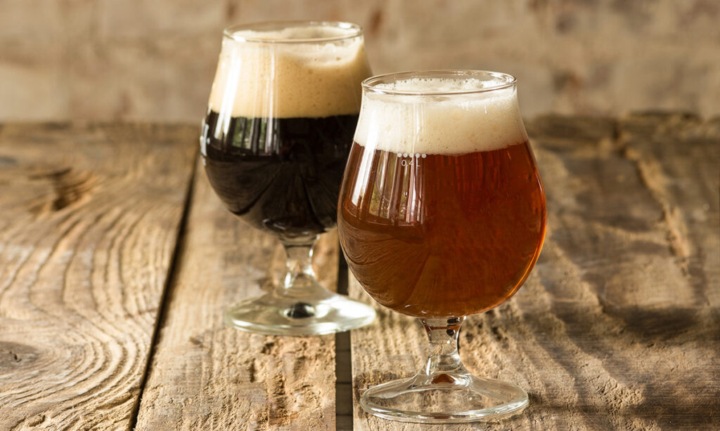 Uma taça de vinho e um copo de cerveja artesanal em uma mesa rústica, representando a combinação perfeita para celebrações no estilo country.