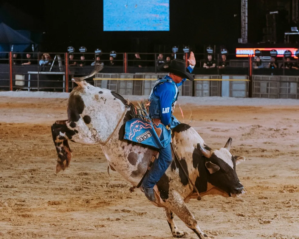 Montaria em touros em um rodeio, com peões mostrando coragem e habilidade em um evento tradicional country.