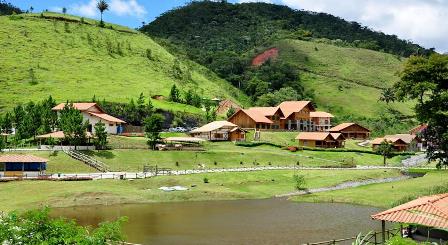 Vista panorâmica de uma fazenda com campos verdes e uma casa de campo típica, representando o turismo rural no Brasil.