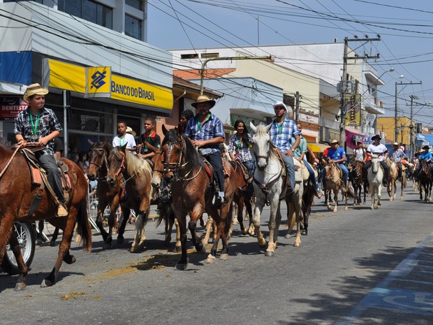 Cavaleiros desfilando com trajes típicos em um evento country.