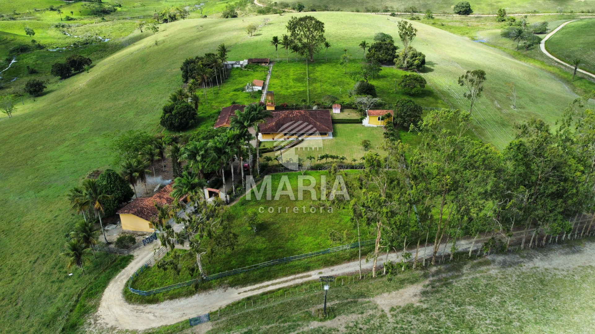 Fazenda verdejante no Brasil, com vastas áreas de pastagem e montanhas ao fundo.