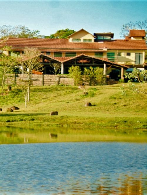 Uma linda paisagem rural com uma fazenda tipicamente country ao fundo, cercada por vastos campos verdes e cavalarias.