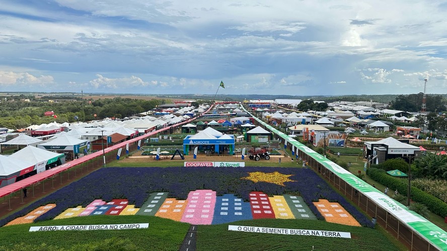 Feira Agropecuária no Paraná com produtores observando expositores e apresentando suas ofertas.