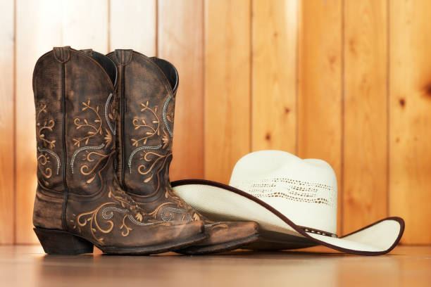 Chapéu e botas country sobre fundo rústico, representando o estilo dos apaixonados por rodeio.