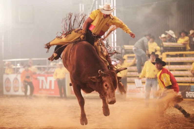 Cavaleiros competindo em um rodeio no Brasil com emoção nas montarias.