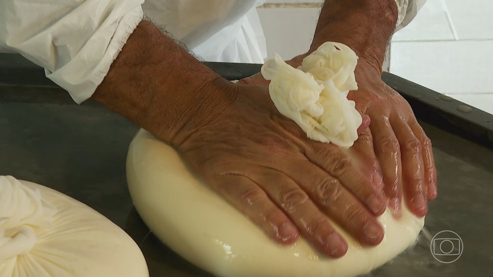 Queijo artesanal fresco sobre uma tábua de madeira, com um fundo de fazenda country.