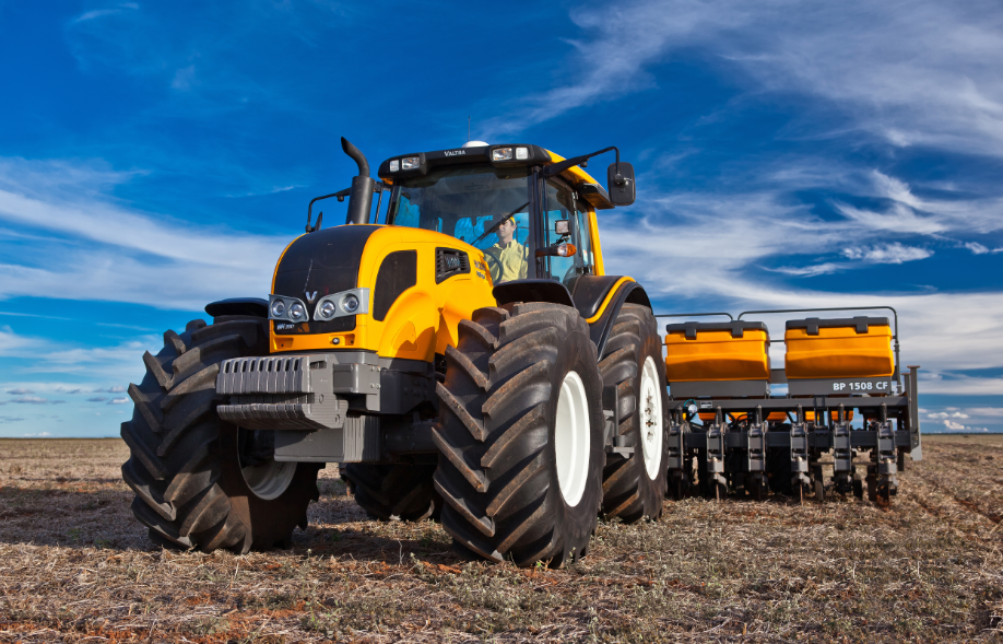 Trator moderno em um campo vasto, simbolizando a tecnologia agrícola.