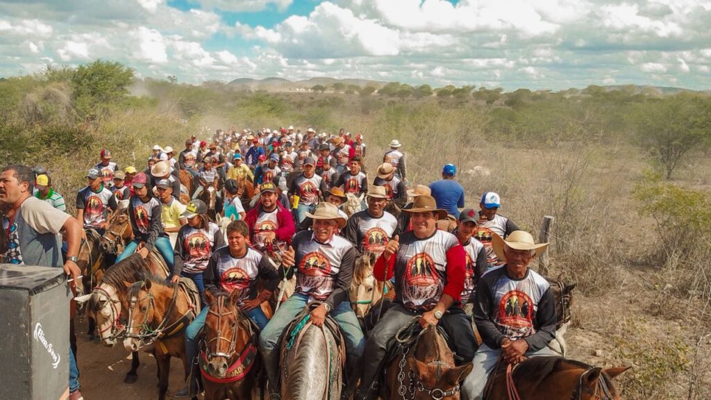 Cavalgada no Sertão com cavaleiros e vaqueiros na paisagem rural.