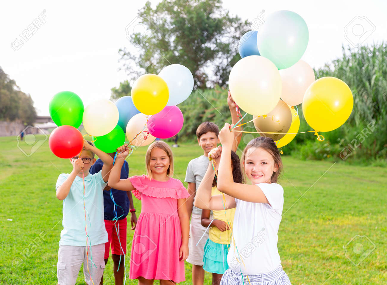 Meninos e meninas brincando com balões no campo, em um ambiente rural alegre e tranquilo.
