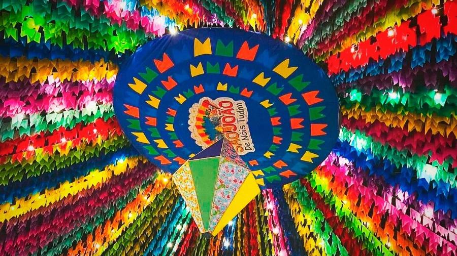 Festa Junina com bandeirinhas e público dançando ao som da sanfona